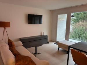 un salon avec un canapé et une télévision au mur dans l'établissement Feel Home Apartments - Seesicht - Terrasse - Parkplatz, à Emmetten