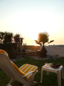 a chair and a table in a yard with the sunset at Vila Mar in Porto Covo