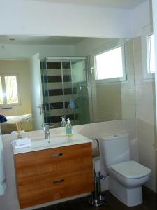 a bathroom with a toilet and a sink and a mirror at Vila Mar in Porto Covo