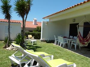 a yard with chairs and a table and a hammock at Vila Mar in Porto Covo