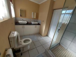 a bathroom with a toilet and two sinks and a shower at Tevreden in Rhodes