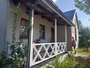a woman standing on the porch of a white house at Tevreden in Rhodes
