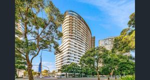 a tall building with trees in front of it at Sydney Olympic Park 13Free Parking in Sydney