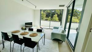 a living room with a table and chairs and a couch at Sydney Olympic Park 13Free Parking in Sydney