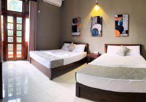 een slaapkamer met twee bedden en een raam bij Osara Holiday Home in Anuradhapura