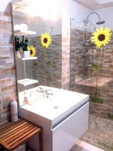 ein Badezimmer mit einem Waschbecken und einer Dusche mit Sonnenblumen in der Unterkunft Eden Part' - Appartement avec jardin privé à Baie-Mahault in Baie-Mahault
