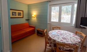 ein Wohnzimmer mit einem Tisch und einem Sofa in der Unterkunft Résidence Vacancéole Les Monts Jura in Lélex