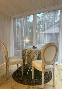 zwei Stühle und ein Tisch in einem Raum mit einem Fenster in der Unterkunft Kulautuva Park Apartments in Kulautuva