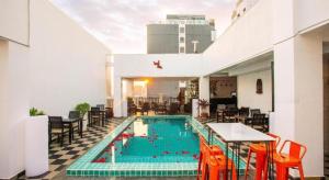 een zwembad met oranje stoelen en een tafel bij Wind Holiday Hotel in Phnom Penh