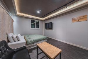 ein Zimmer mit einem Bett, einer Couch und einem Tisch in der Unterkunft V Hotel in Gumi