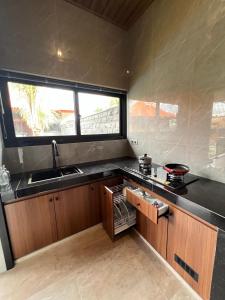 a kitchen with a sink and a stove and a window at Adiuma Cottage Ubud in Ubud