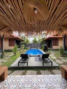 een patio met 2 stoelen en een zwembad bij Adiuma Cottage Ubud in Ubud