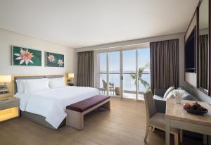 麦克坦Dusit Thani Mactan Cebu Resort的一间配有大床和书桌的酒店房间,以及一间视野开阔的房间。