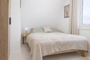 a white bedroom with a bed and a window at Ferienhaus Seeblick Westerwald in Mengerskirchen