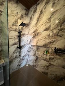 a bathroom with a shower with a stone wall at Adiuma Cottage Ubud in Ubud +7 photos