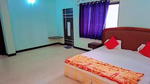 Schlafzimmer mit einem Bett mit roten und orangefarbenen Kissen in der Unterkunft Sai Dwarka Alibag Hotel in Alibag + 71 Fotos