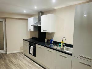 a kitchen with white cabinets and a sink at Executive 2 Bed Condo with Free Parking in Manchester