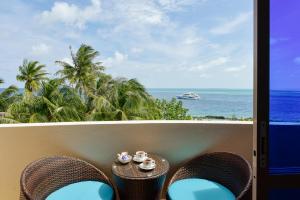 a balcony with chairs and a table with a view of the ocean at Season Paradise in Thulusdhoo