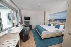 une chambre avec un lit, un bureau et une fenêtre dans l'établissement Hotel Haus am Meer, à Graal-Müritz