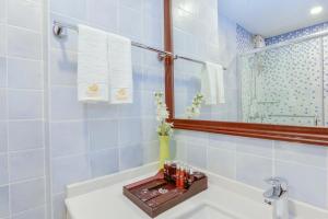 a bathroom with a sink and a mirror and a tub at Season Paradise in Thulusdhoo