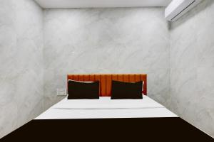 a bedroom with a bed with two black pillows at Hotel O Lotus in Surat