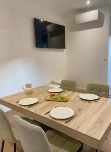 een houten tafel met stoelen en borden en een televisie bij Appartement Du Lot in Entraygues-sur-Truyère