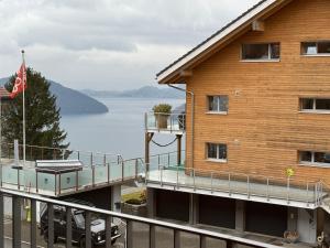 un bâtiment avec un drapeau au bord d'un lac dans l'établissement Feel Home Apartments - Seeblick - Bergblick - Parkplatz, à Emmetten