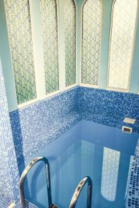 a bathroom with a blue tiled tub with three windows at Hotel Atlantida in Kislovodsk