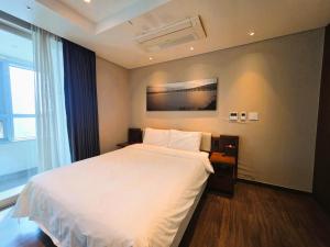 een slaapkamer met een wit bed en een raam bij Haeundae W Residence Hotel in Busan +34 foto's