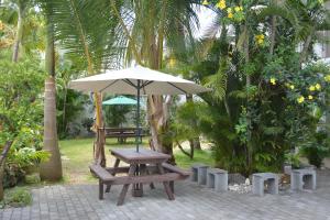 einen Picknicktisch und einen Regenschirm in einem Park in der Unterkunft La Perla Holiday Apartments in Pereybere