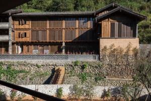 a building with a stone wall in front of it at Tsingpu Tulou Retreat 青普文化行馆 南靖土楼店 in Futian