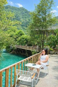 een vrouw die aan een tafel zit te praten op een mobiele telefoon bij Mộc Sơn Homestay in Mộc Châu