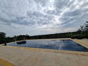 a large swimming pool under a cloudy sky at Cozy Country House with Pool in Ban Nong Nam Khem