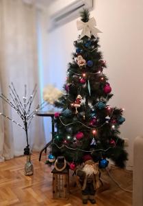 a christmas tree with ornaments on a wooden floor at Apartman Ozy in Kraljevo