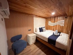 纳闽巴霍Phinisi Shared Boat Komodo的一间卧室，有一张床和一把蓝色椅子
