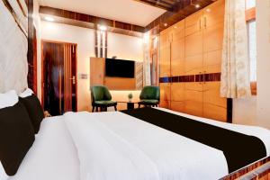 een slaapkamer met een bed en 2 stoelen en een televisie bij Hotel O Siris Luxury Cottage Amatra Dunsvirk Court in Mussoorie +25 foto's