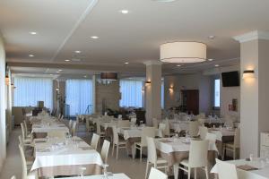 a dining room with white tables and white chairs at Hotel Rizzi in Castel San Giovanni