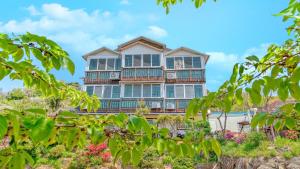 een groot huis met balkons en bomen bij Ganghwa Ara Pension in Incheon