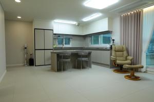 a large kitchen with a counter and chairs in a room at Two Rest Pension in Damyang