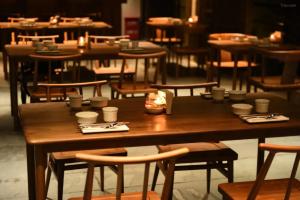 een houten tafel met kopjes en borden erop bij Tsingpu Tulou Retreat 青普文化行馆 南靖土楼店 in Nanjing