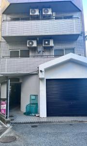 a building with a garage with a door at Tanuki Inn Korien Kyoto Osaka in Neyagawa