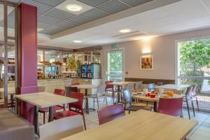 een restaurant met tafels en stoelen en een keuken bij Ace Hotel Bourges in Bourges