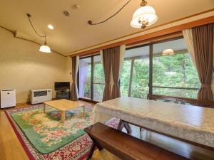 een woonkamer met een tafel en een groot raam bij Runesu Karuizawa - Vacation STAY 78428v in Tsumagoi