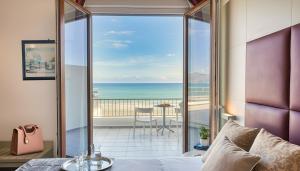 een slaapkamer met een bed en uitzicht op de oceaan bij Hotel La Battigia in Alcamo Marina