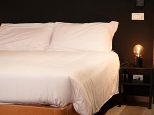 a bed with white sheets and a light on a table at Grifone Dolomiti Residences in Arabba +94 photos