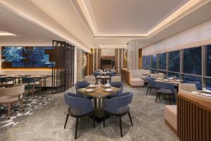 ein Restaurant mit blauen Stühlen und Tischen und Fenstern in der Unterkunft Four Points by Sheraton Amritsar, Mall Road in Amritsar