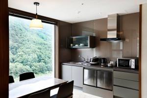 a kitchen with a table and a large window at Pine Forest Jeongseon Alpine Resort in Jeongseon