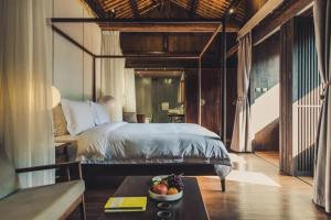 a bedroom with a bed and a bowl of fruit on a table at Tsingpu Tulou Retreat 青普文化行馆 南靖土楼店 in Futian