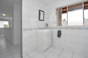 een witte badkamer met een wastafel en een spiegel bij Sandton Elite Stay in Sandton +33 foto's