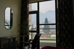 a room with a window with a table and a chair at LVMR RIDERS REST Homestay in Kulu